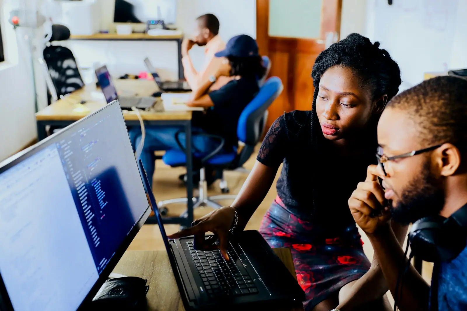Two colleagues learning together at a laptop in an open office
